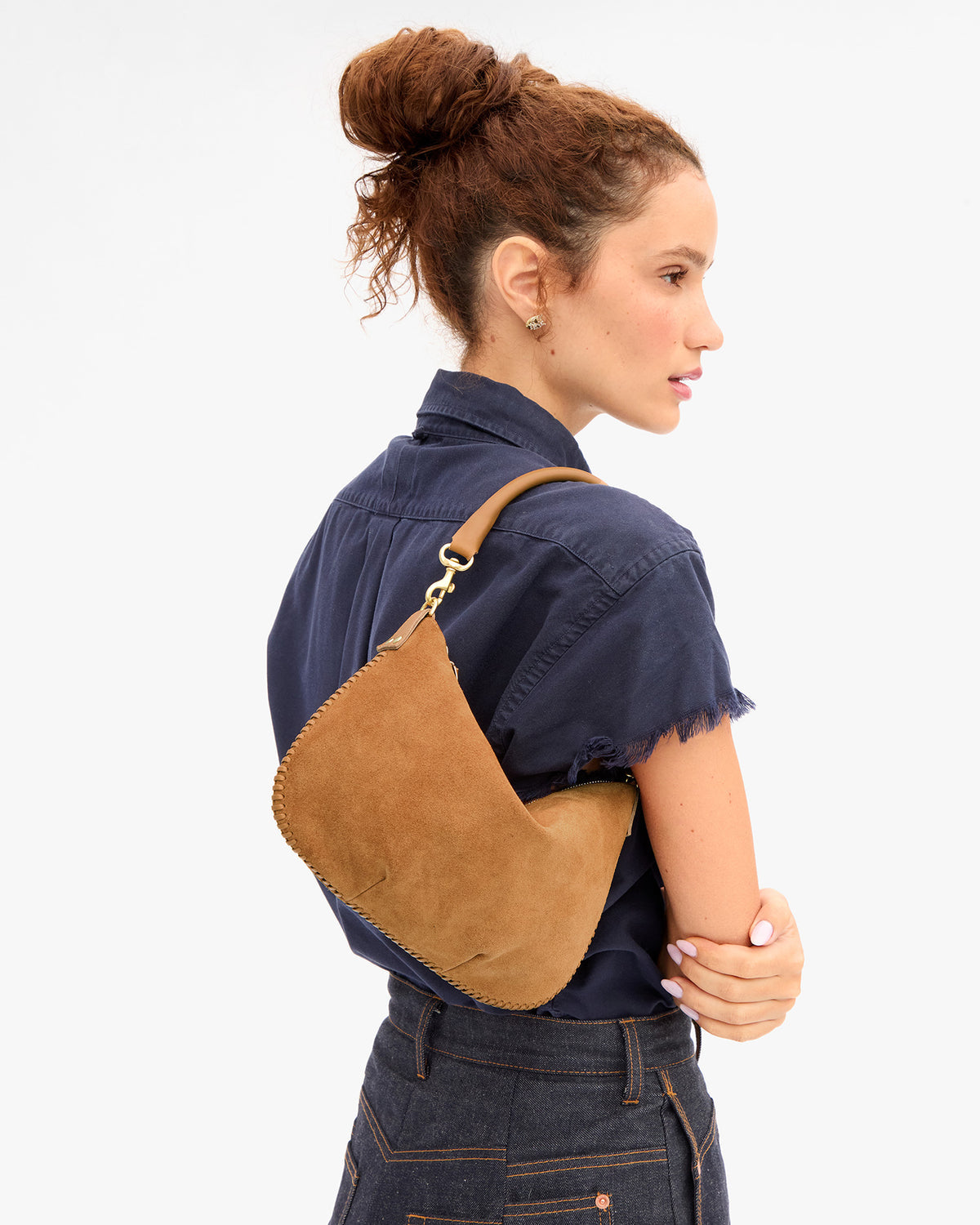 Clare V Petit Moyen Messenger in Caramel Suede worn as a shoulder bag by a model